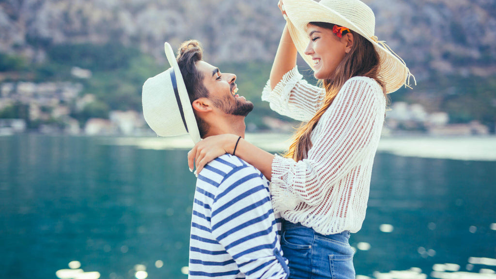 Una pareja encantada comparte un momento íntimo de felicidad y conexión junto al mar, rodeados de un paisaje sereno y acogedor.